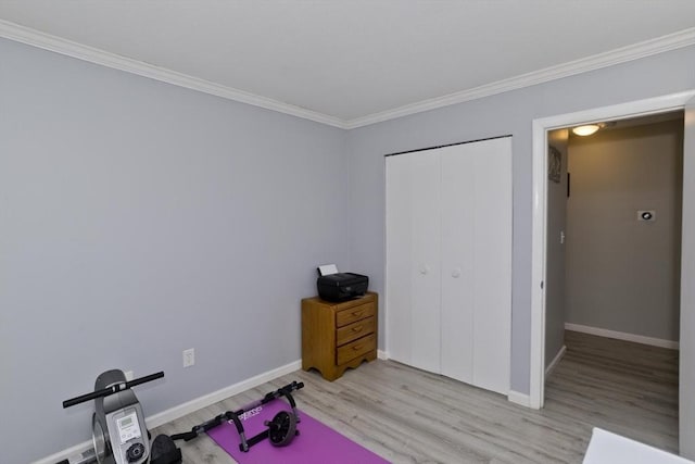 workout area with baseboards, light wood finished floors, and crown molding