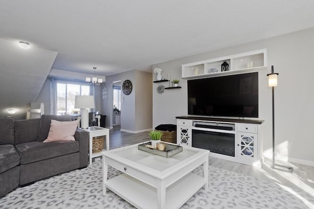 living room featuring baseboards, light wood-style floors, and a notable chandelier