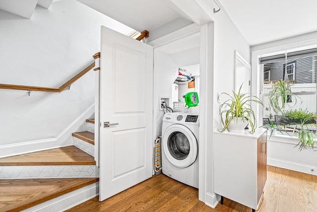 clothes washing area featuring baseboards, washer / clothes dryer, wood finished floors, and laundry area