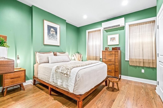 bedroom with recessed lighting, baseboards, light wood finished floors, and a wall mounted AC