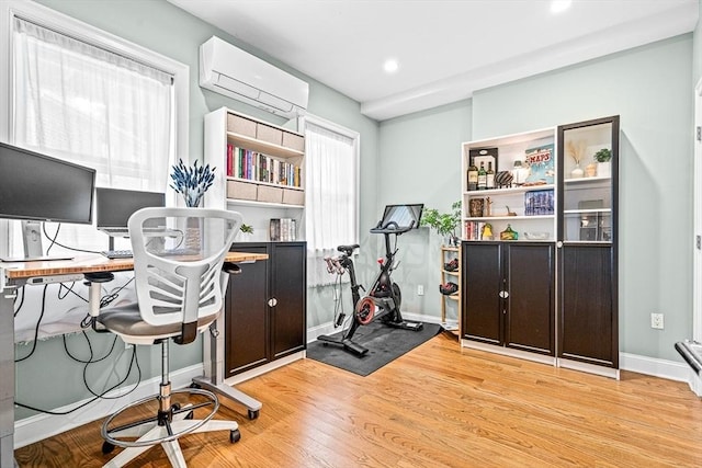 office with baseboards, light wood-type flooring, plenty of natural light, and an AC wall unit