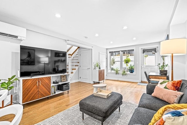 living room with an AC wall unit, light wood-style flooring, recessed lighting, baseboards, and stairs