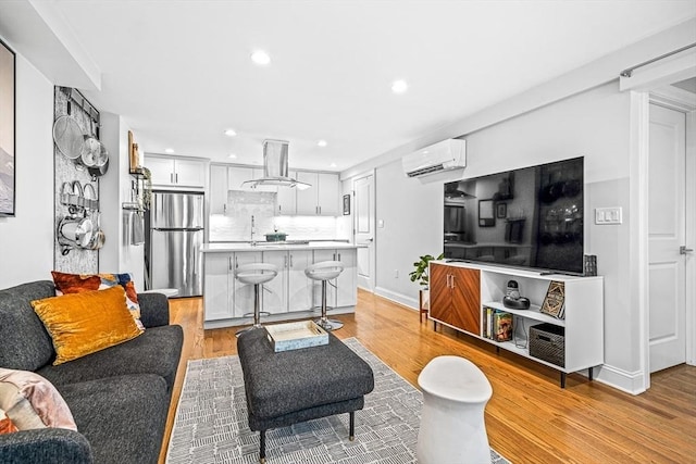 living area with recessed lighting, baseboards, an AC wall unit, and light wood finished floors