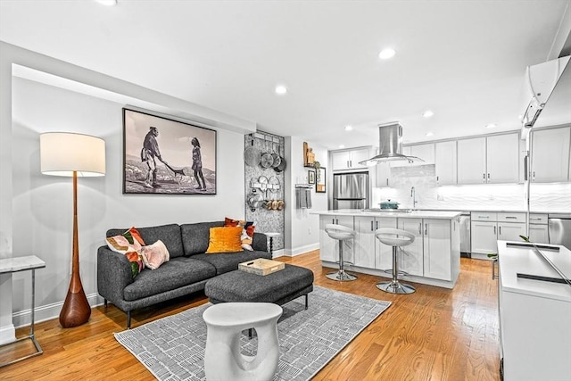 living area with light wood finished floors, recessed lighting, and baseboards