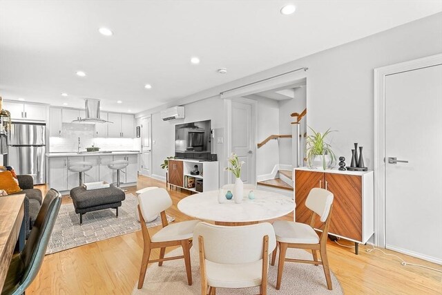 dining space with recessed lighting, light wood-style flooring, stairs, and a wall unit AC