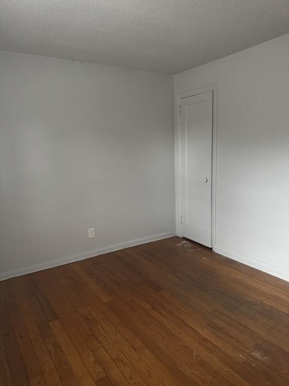 spare room with dark wood-type flooring and a textured ceiling