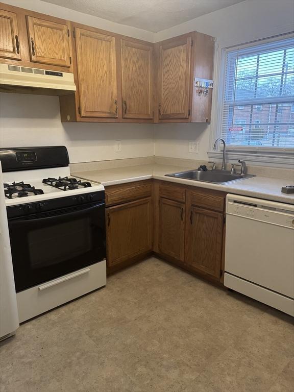 kitchen featuring white dishwasher, sink, and gas range