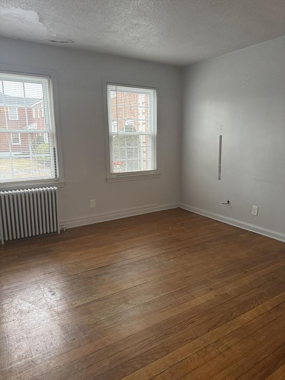 spare room with radiator heating unit, dark hardwood / wood-style floors, a textured ceiling, and plenty of natural light