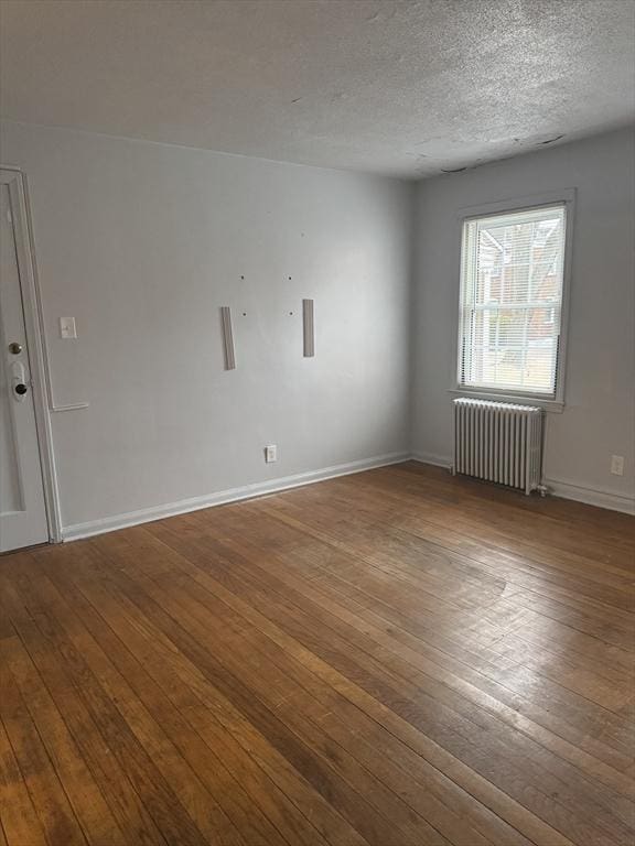 unfurnished room featuring radiator, hardwood / wood-style floors, and a textured ceiling