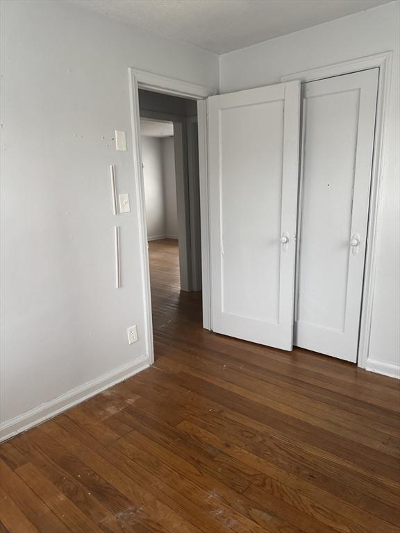 unfurnished bedroom with dark hardwood / wood-style flooring and a closet