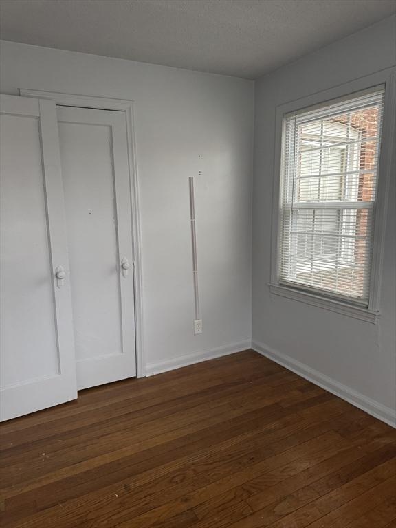 unfurnished bedroom featuring dark wood-type flooring, a closet, and a textured ceiling