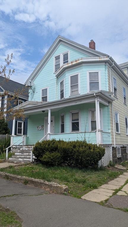 view of front facade with covered porch and a chimney