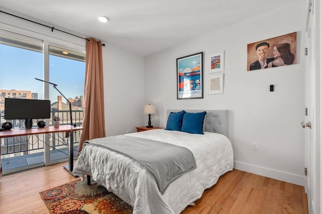 bedroom with access to outside and hardwood / wood-style floors