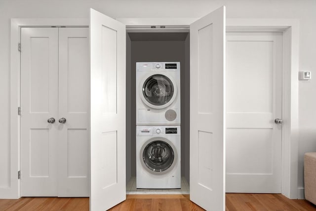 laundry area featuring light hardwood / wood-style floors and stacked washing maching and dryer