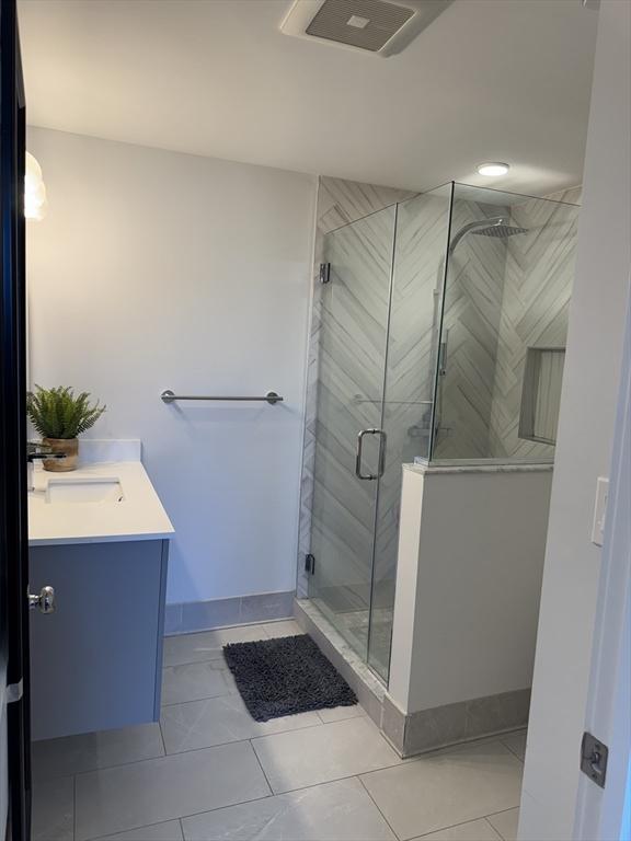 bathroom featuring a shower with shower door, vanity, and tile patterned flooring