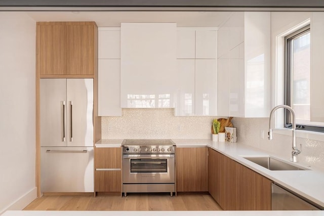 kitchen with stainless steel appliances, white cabinetry, light hardwood / wood-style floors, and sink