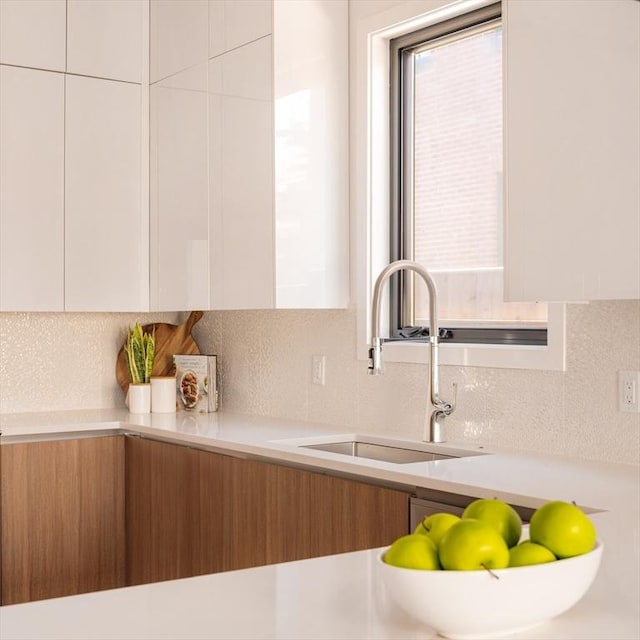 kitchen with tasteful backsplash, sink, and white cabinets