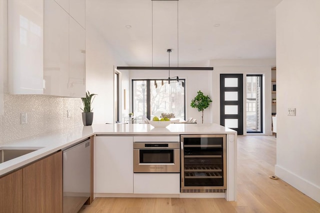 kitchen with white cabinetry, stainless steel appliances, wine cooler, backsplash, and pendant lighting