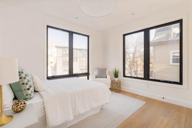 bedroom with light hardwood / wood-style floors and multiple windows