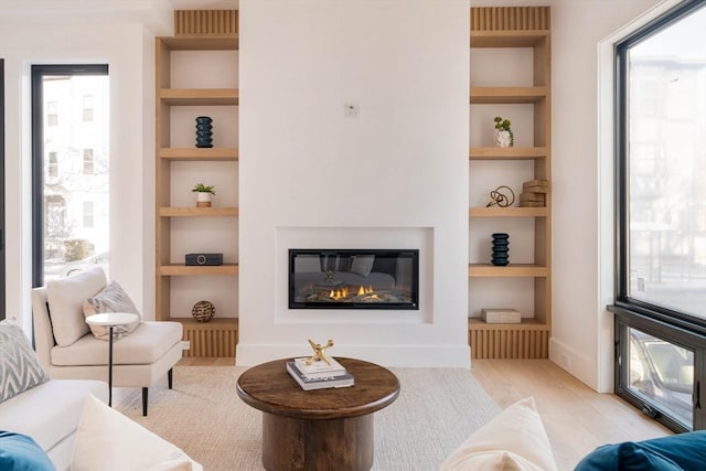 living room with built in shelves and light hardwood / wood-style flooring