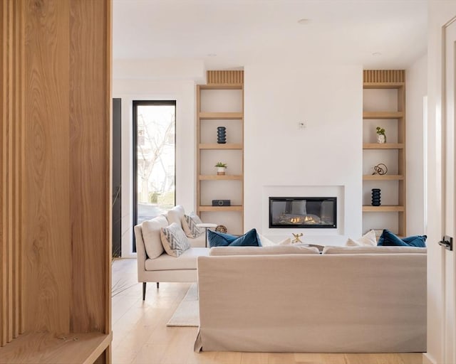 living room with built in shelves and light hardwood / wood-style floors