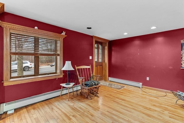 living area featuring baseboard heating and wood-type flooring