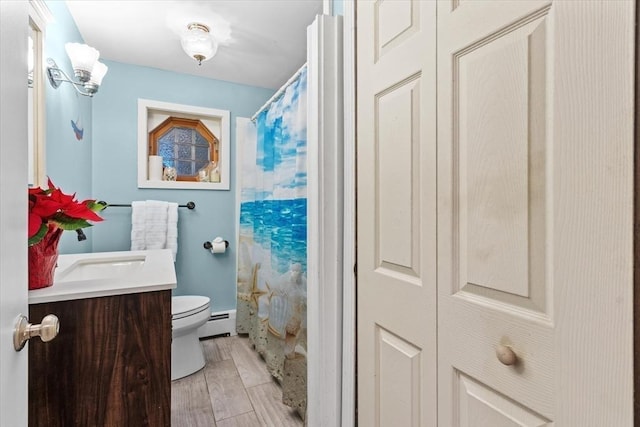 bathroom with toilet, vanity, a baseboard heating unit, and a shower with curtain