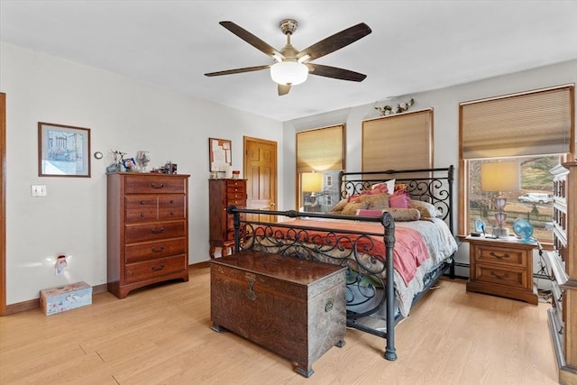 bedroom featuring a baseboard heating unit, ceiling fan, and light hardwood / wood-style floors