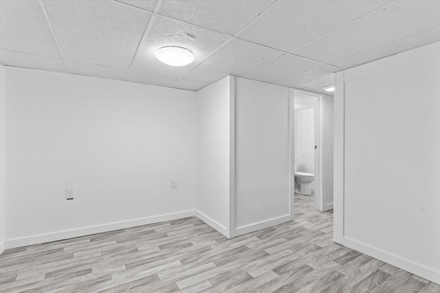 spare room featuring light wood-type flooring and a drop ceiling