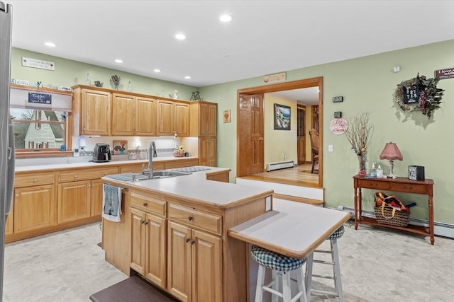 kitchen with sink, a center island with sink, a breakfast bar area, and baseboard heating