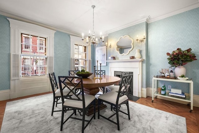 dining area featuring parquet floors, crown molding, a high end fireplace, and an inviting chandelier