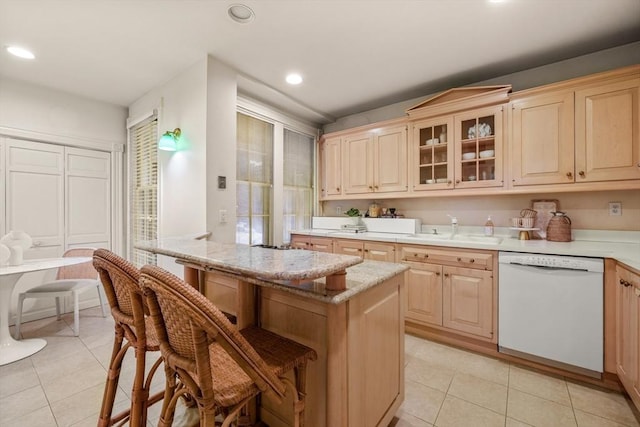 kitchen with light brown cabinetry, sink, light tile patterned floors, dishwasher, and a center island