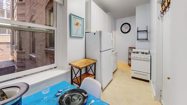 kitchen featuring white appliances, white cabinets, and baseboards