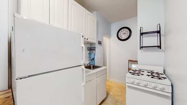 kitchen with baseboards, light countertops, white appliances, white cabinetry, and a sink