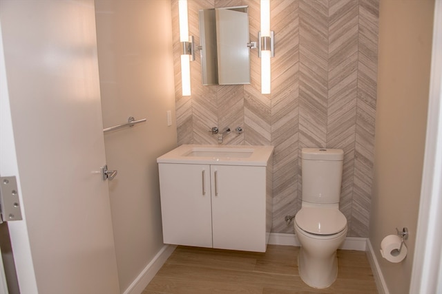 bathroom featuring wood-type flooring, vanity, toilet, and tile walls