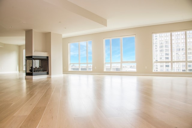 unfurnished living room with a multi sided fireplace and light wood-type flooring