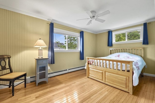 bedroom featuring light wood-type flooring, baseboard heating, ceiling fan, and crown molding