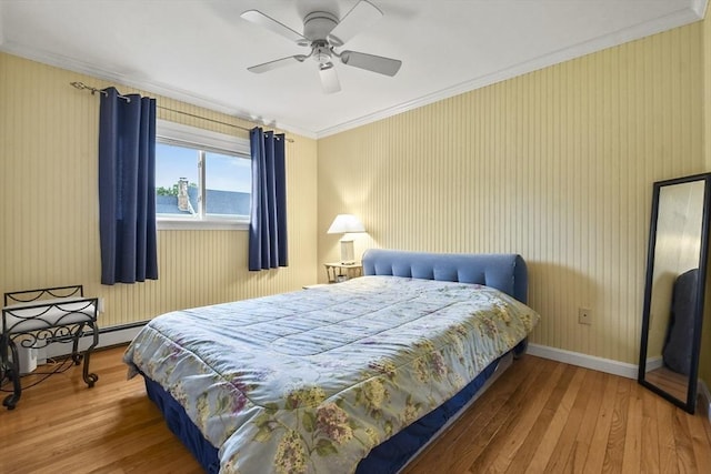 bedroom featuring ornamental molding, a baseboard heating unit, ceiling fan, and wood-type flooring