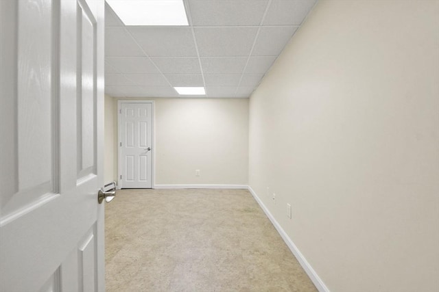 carpeted spare room with a baseboard radiator and a paneled ceiling