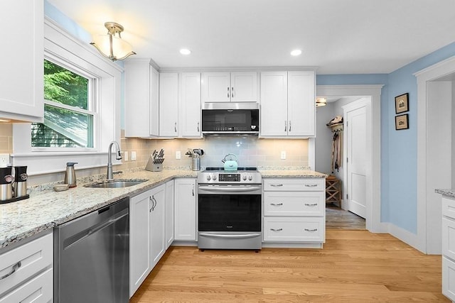 40 Maple St, Mansfield, MA 02048 - kitchen featuring appliances with stainless steel finishes, decorative backsplash, white cabinetry, light wood finished floors, and light stone countertops