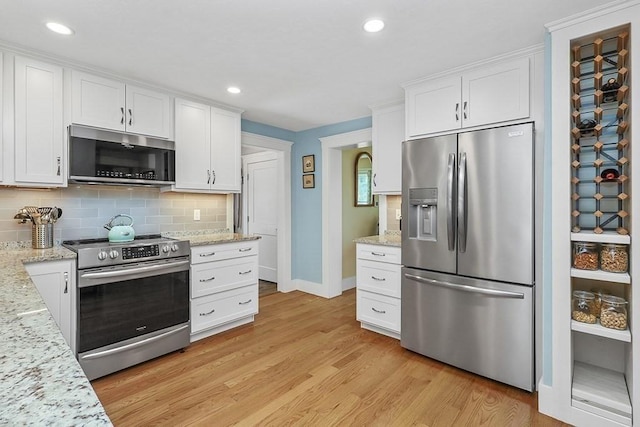 40 Maple St, Mansfield, MA 02048 - kitchen with appliances with stainless steel finishes, light wood finished floors, white cabinets, backsplash, and recessed lighting