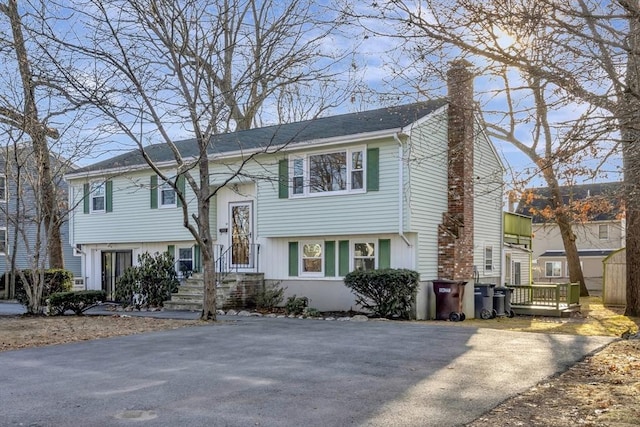 bi-level home featuring aphalt driveway and a chimney