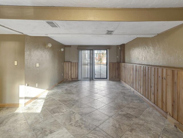 basement featuring a textured ceiling, rail lighting, and wooden walls