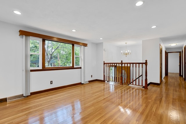 spare room with light hardwood / wood-style floors and a notable chandelier