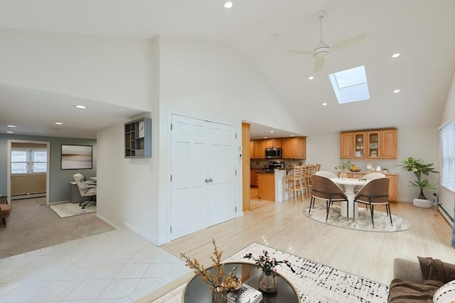 living room with baseboard heating, a skylight, ceiling fan, and high vaulted ceiling