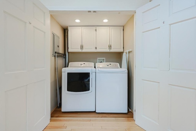 laundry room featuring cabinets, separate washer and dryer, and light hardwood / wood-style flooring