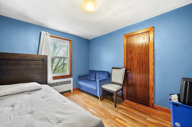 bedroom featuring radiator heating unit, wood finished floors, and baseboards