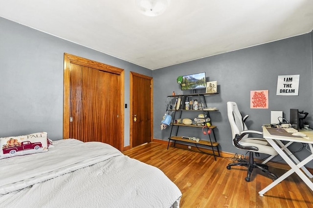 bedroom featuring wood finished floors, baseboards, and a desk