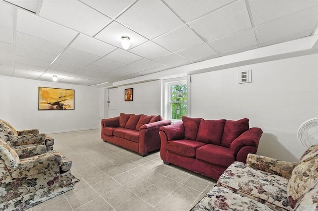 living room featuring a paneled ceiling, light tile patterned floors, and baseboards