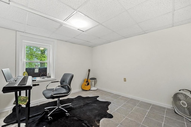 tiled office space featuring a paneled ceiling and baseboards